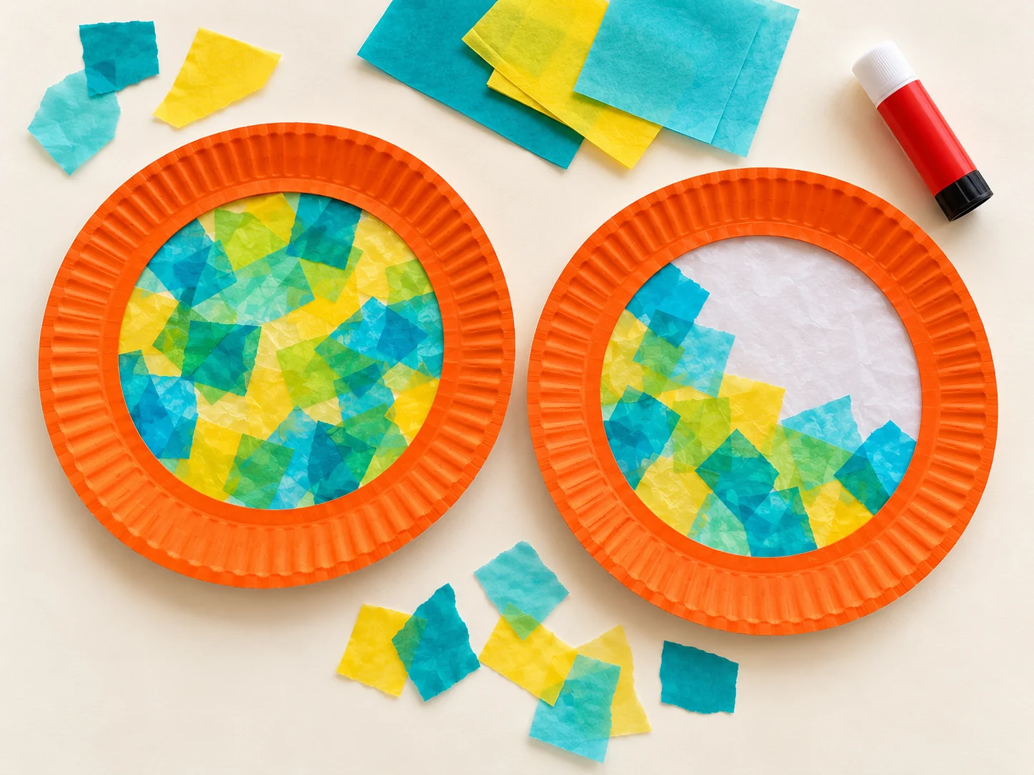 Zwei orange Papptellerringe mit Transparentpapierfenstern: eines ist bunt beklebt, beim zweiten ist die weiße Grundlage noch sichtbar.